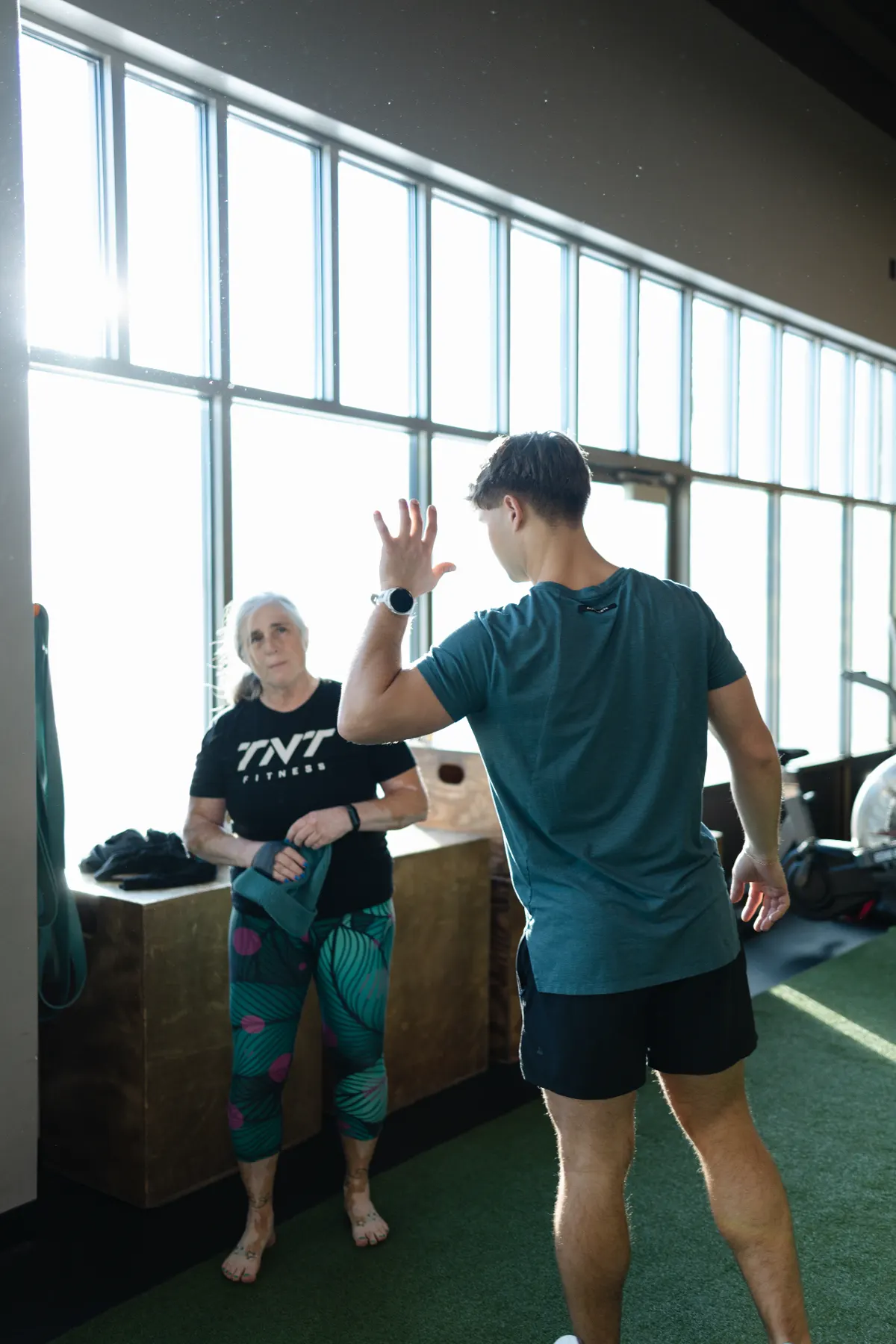 TNT Fitness coach demonstrating a lift to an adult member during a coached session