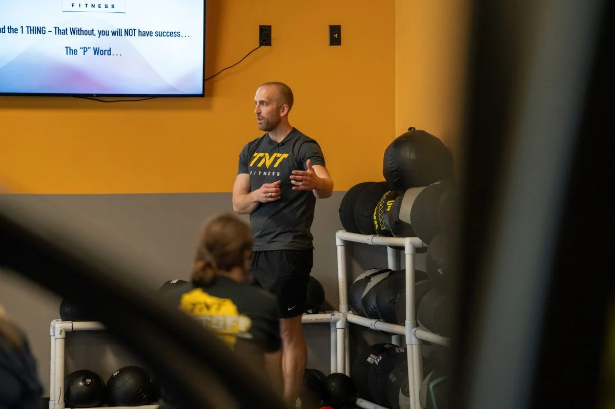 TNT Fitness coach talking a group of adult members through the plan before a session