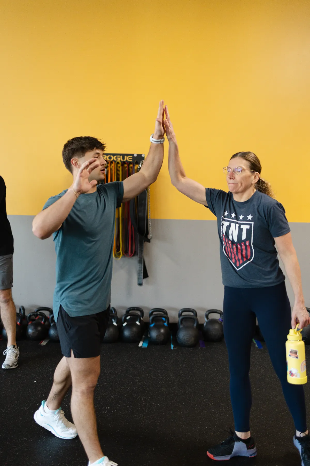 Two adult members high-fiving after finishing a coached training session at TNT Fitness