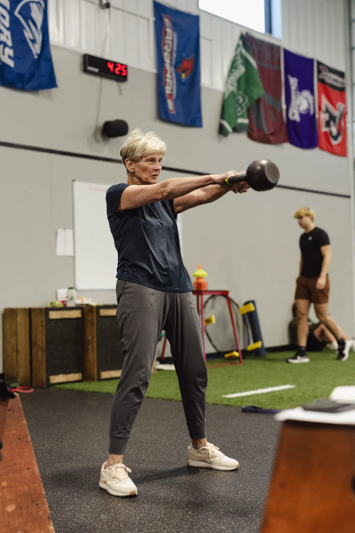 Adult member performing a kettlebell swing during a large group session at TNT Fitness
